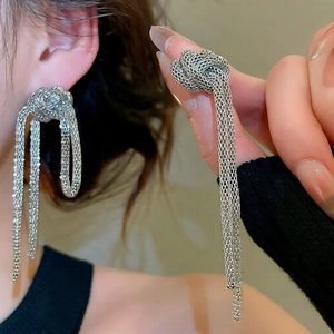 Detail of silver knot stud earrings with long flexible metallic mesh fringe tassels