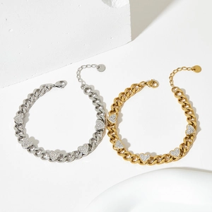 Gold and silver Cuban link bracelets with sparkling zircon heart charms on stone background