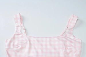 Detail view of pink and white checkered dress neckline and adjustable shoulder straps