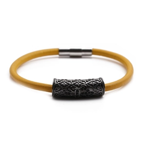 Detail view of yellow leather bracelet with engraved vintage grey metal cross charm