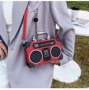 Detail of red radio shaped handbag with metal handle and BOOM text in an outdoor setting