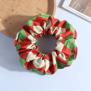 Detailed view of plush red and green argyle fabric scrunchie on wooden tray