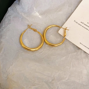 Detailed macro view of polished gold hoop earrings featuring a sleek metallic finish