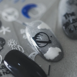Matte finish nail stickers with black Saturn and moon designs on silver glitter nails