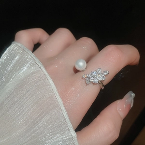 Detail of silver bow ring with white pearl and sparkling zircon stones on finger