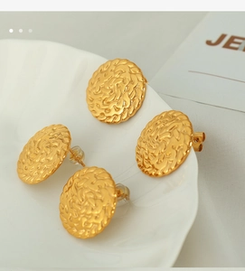 Macro detail of gold round woven textured earrings with silicone backs on white tray