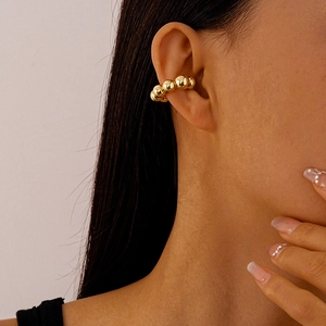 Close-up of a gold beaded metal ear cuff worn on the cartilage without piercing