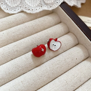 Macro shot of creative red and white apple-shaped earrings with fine enamel texture