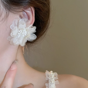 Detailed view of cream mesh flower earrings featuring central pearl bead on model