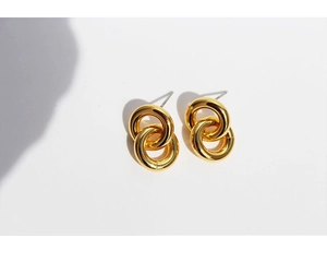 Detailed close-up of gold-plated double interlocking circular stud earrings on white background