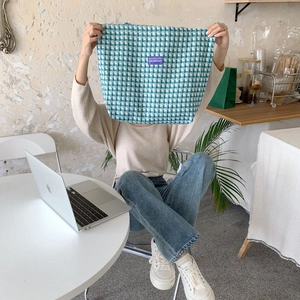 Detail of blue checkerboard canvas tote with purple logo label in a cozy office setting