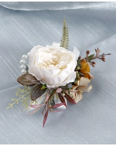Macro shot of white fabric peony wrist corsage with artificial pearls and green leaves