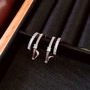 Close-up of silver C-shaped double-layered earrings with pavé zircons in a jewelry box