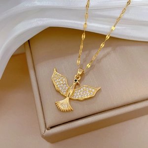 Luxurious gold-tone bird pendant necklace with sparkling crystals on a premium display