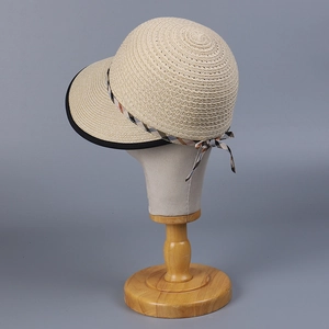 Close-up of beige straw sun hat with checkered ribbon bow detail and black trim