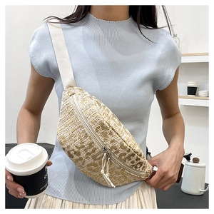 Detail of woven straw fanny pack texture with cream strap and zip knot puller