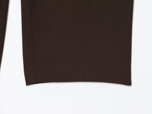 Detailed macro view showing the double-stitched hem and woven texture of brown suit pants