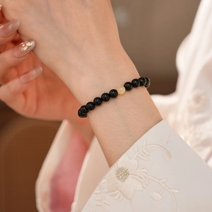 Detail of black obsidian beaded bracelet with yellow accent bead on person wrist
