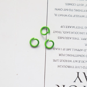 Macro shot of three green metal open jump rings for DIY jewelry making on white background