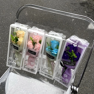 Gift set of four colorful soap flower bouquets in transparent boxes on a chair