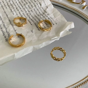 Detailed view of four assorted gold vintage rings on a retro newspaper and mirror surface