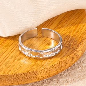 Detail of silver fish tail ring featuring embossed sun star patterns on adjustable band