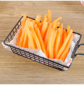 Close-up of artificial sweet potato fries in a black metal basket on wooden surface