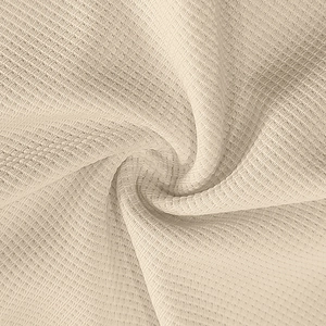 Close-up of beige waffle knit fabric texture showing high-quality fibers and soft drape