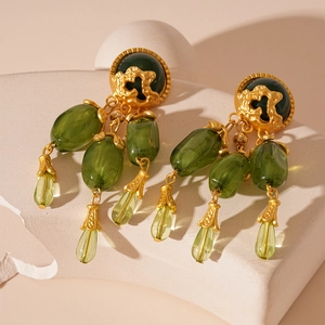 Détail de boucles d'oreilles dorées vintage avec perles en résine vert olive sur pierre