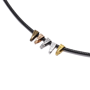 Détail de cinq fermoirs mousquetons en bronze et or sur un cordon en cuir ciré noir