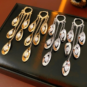 Détail de boucles d'oreilles à pompons en zircon doré et argenté sur cuir noir