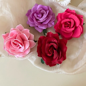 Detailed top view of four handmade fabric rose hair clips in pink and purple tones