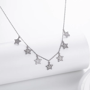 Detail view of S925 silver necklace with seven sparkling star charms on white pedestal