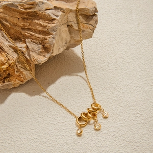 Detailed shot of 18K gold stainless steel necklace with sparkling crystal ring pendants