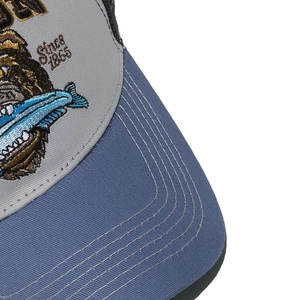 Dettaglio ricamo orso e cuciture della visiera su cappellino da baseball in cotone