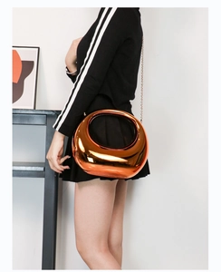 Close-up of bronze metallic acrylic bag with hollow circular handle and thin chain strap