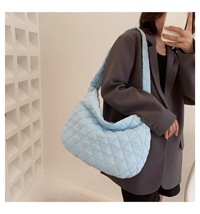 Close-up of light blue quilted puffer bag featuring a soft ruched texture and shoulder strap