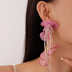 Close-up of handmade pink lace flower earrings with beaded long tassels on model