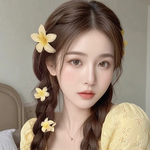 Detail view of yellow plumeria hair claw clip worn by a model for vacation hairstyle