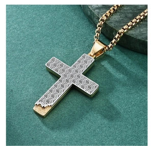 Detail of a bicolored honeycomb cross pendant with gold box chain on green marble