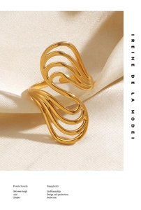 Close-up of golden wavy open ring on beige silk background with soft lighting