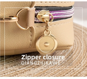 Detail of golden zipper and hardware on beige pebble leather crossbody camera bag