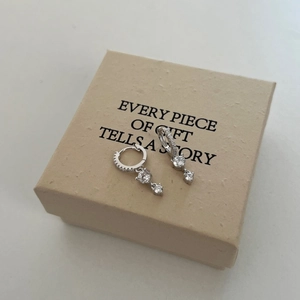 Detail of S925 sterling silver heart earrings with zircons on a beige gift box