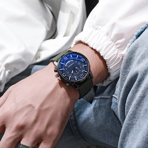 Detail of blue dial quartz watch with black silicone strap on wrist with denim jacket