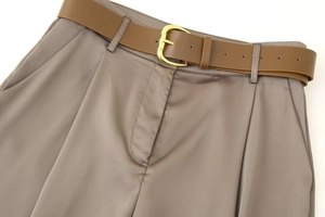 Detailed close-up of brown satin wide-leg pants featuring a waist belt and golden buckle