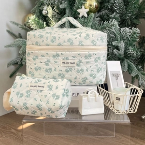Detail view of large square and small cylindrical floral quilted pouches in white and green