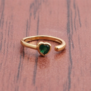 Detail of gold-plated adjustable ring featuring a green heart-shaped faceted gemstone