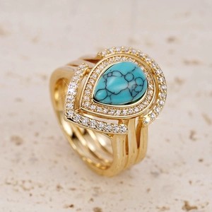 Close-up of golden teardrop turquoise ring with double halo white zircon stones