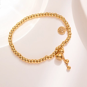 Golden beaded bracelet with Fu character and gourd pendants on an ivory background
