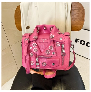 Detail of pink jacket-shaped bag with metal zippers, rhinestones and floral accents